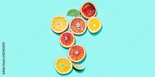 Composition with slices citrus fruits  grapefruit  red orange  lemon  lime on turquoise. Summer food flat lay with daylight.