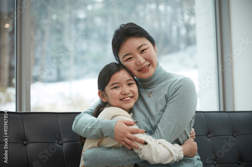 Little kid daughter and old mother while sitting on sofa at home