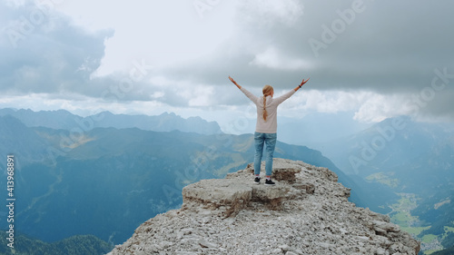 Young woman with outstretched arms enjoying the beauty of nature on mountain rock. Fantastic landscape view.