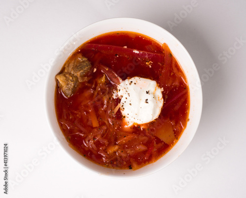 Borscht in a white round bowl. Red Ukrainian soup. Studio photo on white background