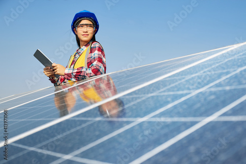 Female energy engineer holding a tablet at a solar panel.