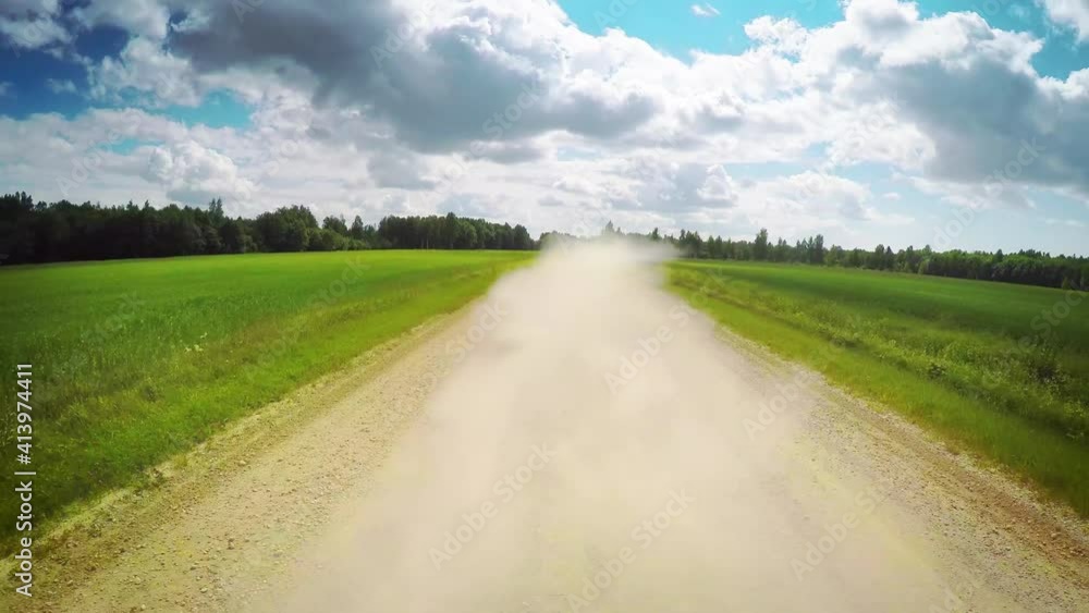 Countryside idyllic nature, POV drive back view, gravel dusty local road, green farm fields, blue sky clouds summer day, car travel gopro point of view