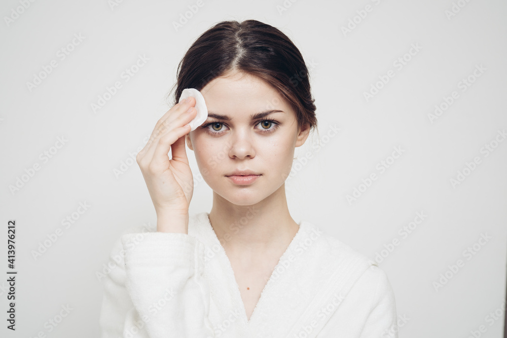 woman in light clothes wipes her face with a soft sponge clean skin cosmetology woman in light clothes wipes her face with a soft sponge clean skin cosmetology