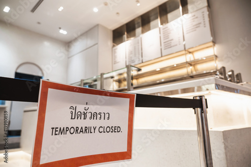 TEMPORARIRY CLOSED text with thai language with the same meaning on the Billboard in front of restaurant or coffee shop in department store