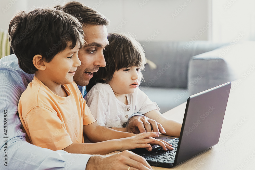 Exited father showing something on laptop to little sons. Adorable Caucasian boys learning computer at home with help of loving middle-aged dad. Fatherhood, childhood and digital technology concept Exited father showing something on laptop to little sons. Adorable Caucasian boys learning computer at home with help of loving middle-aged dad. Fatherhood, childhood and digital technology concept