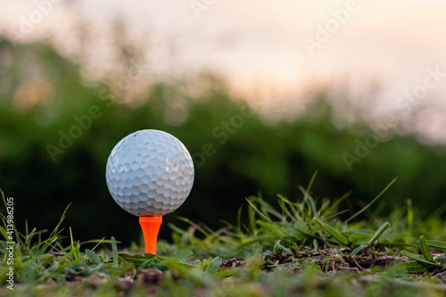 close-up of golf ball and club on green with sunset light