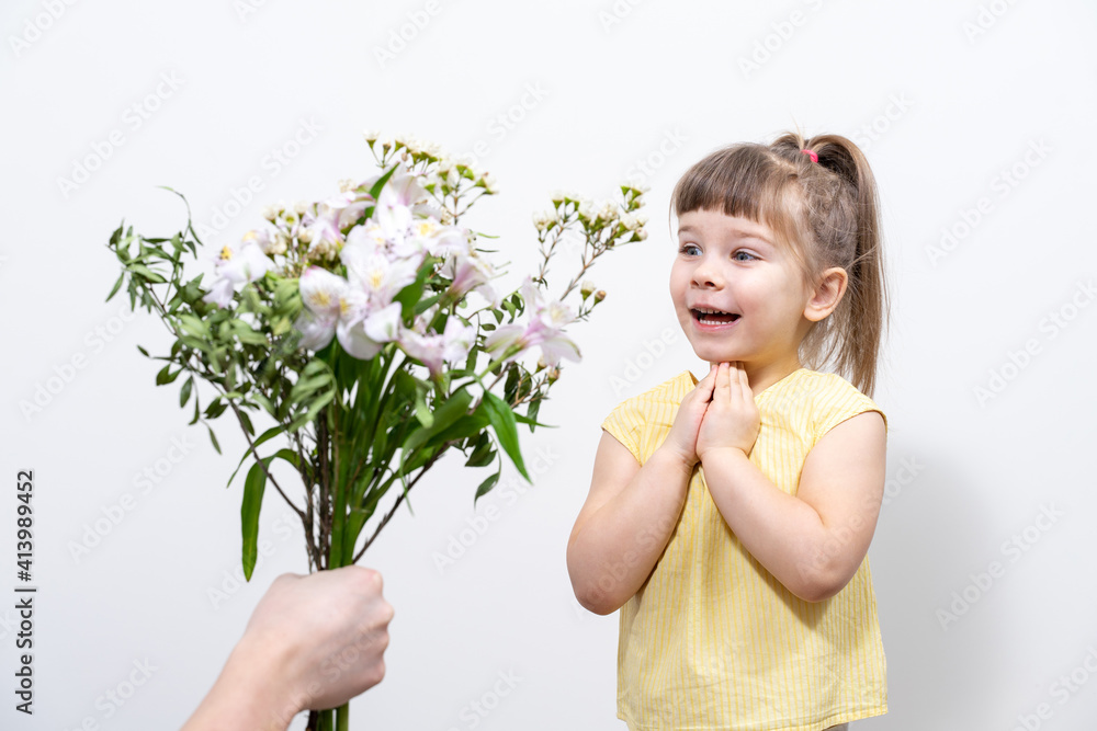 a man's hand holds out a bouquet of white flowers to a cute little girl in a yellow blouse a man's hand holds out a bouquet of white flowers to a cute little girl in a yellow blouse