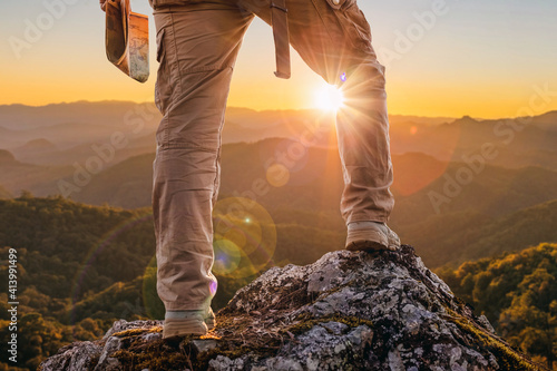 Tablou canvas Hiker standing on top mountain sunset background