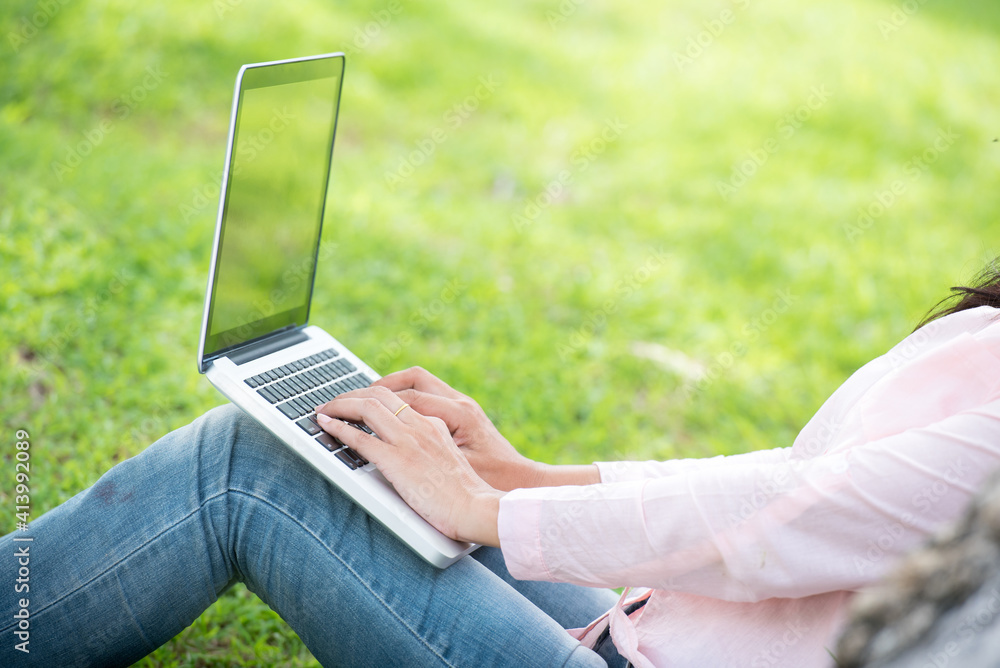 Asian woman sitting green park using laptop computer. Woman working on laptop happy entrepreneur business using notebook with hands typing on keyboard home office during coronavirus quarantine period Asian woman sitting green park using laptop computer. Woman working on laptop happy entrepreneur business using notebook with hands typing on keyboard home office during coronavirus quarantine period