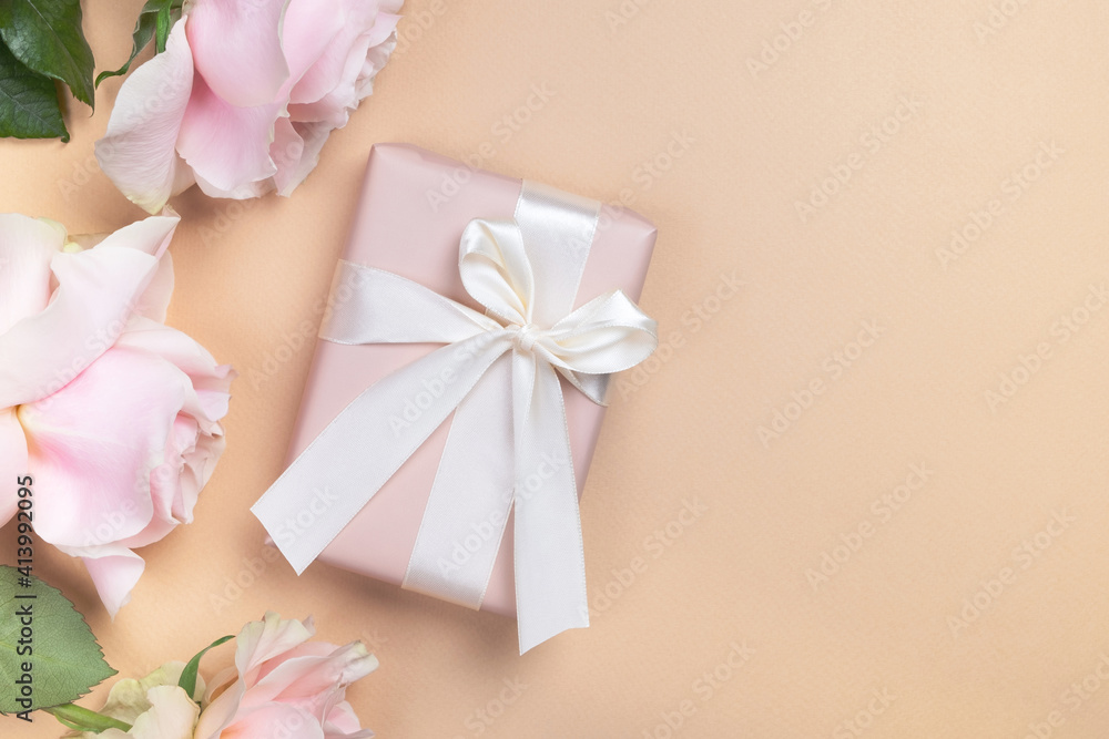 Gift box with roses flowers on pastel beige background. Mothers day, womens day or anniversary postcard. Top view, flat lay, copy space Gift box with roses flowers on pastel beige background. Mothers day, womens day or anniversary postcard. Top view, flat lay, copy space