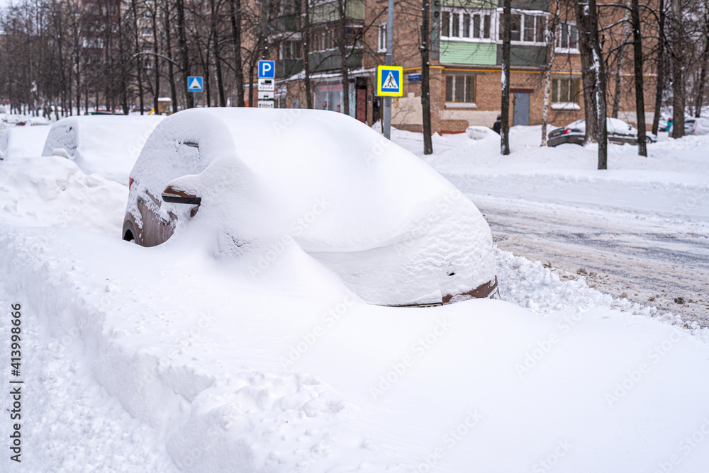 Car snow covered parked near the apartment buildings during a heavy snowfall Car snow covered parked near the apartment buildings during a heavy snowfall