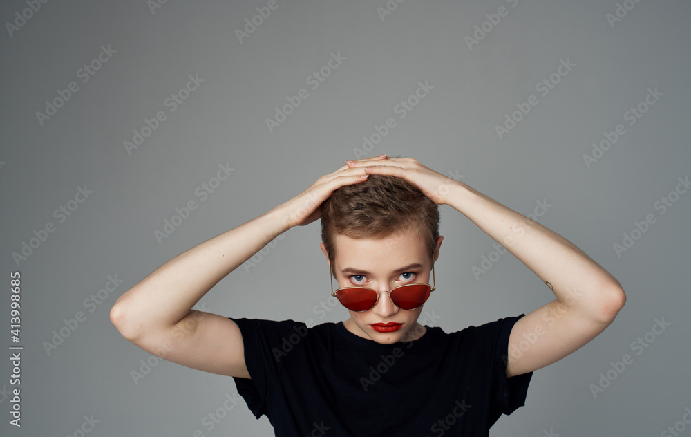 Woman with short hair and makeup dark glasses fashion black t-shirt gray background Woman with short hair and makeup dark glasses fashion black t-shirt gray background