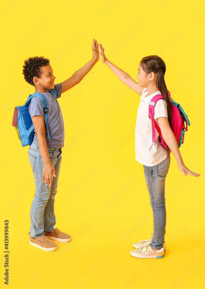 Little schoolchildren greeting each other on color background Little schoolchildren greeting each other on color background