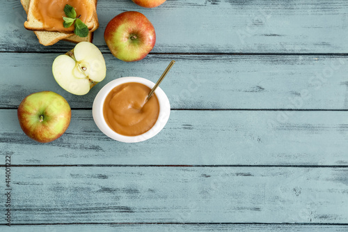 Bowl with sweet apple jam on color wooden background
