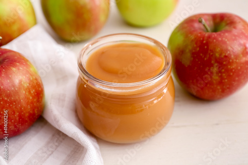 Jar with sweet apple jam on light background