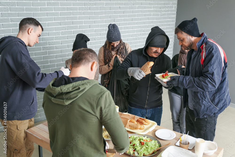 Volunteers giving food to homeless people in warming center foto de ...