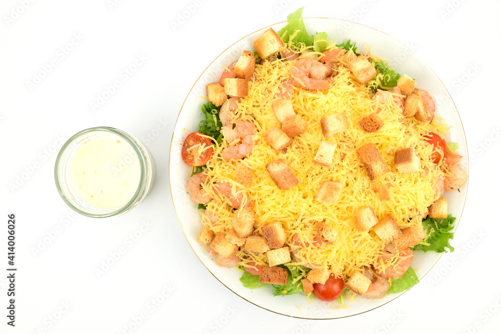 Top view of a plate of shrimp salad sprinkled with cheese crumbs and white bread croutons. A jar of white sauce is nearby Top view of a plate of shrimp salad sprinkled with cheese crumbs and white bread croutons. A jar of white sauce is nearby
