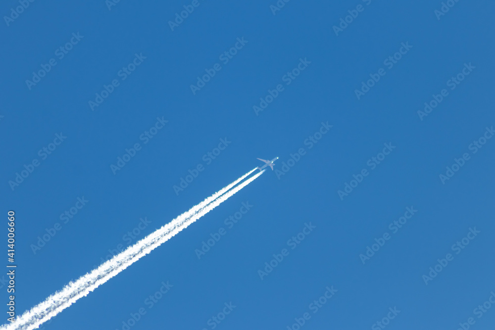 Flying airplane on a journey through the blue sky with a long white smoking exhaust plume and jetwash shows international transportation and globalization transatlantic holidays with pilots Flying airplane on a journey through the blue sky with a long white smoking exhaust plume and jetwash shows international transportation and globalization transatlantic holidays with pilots