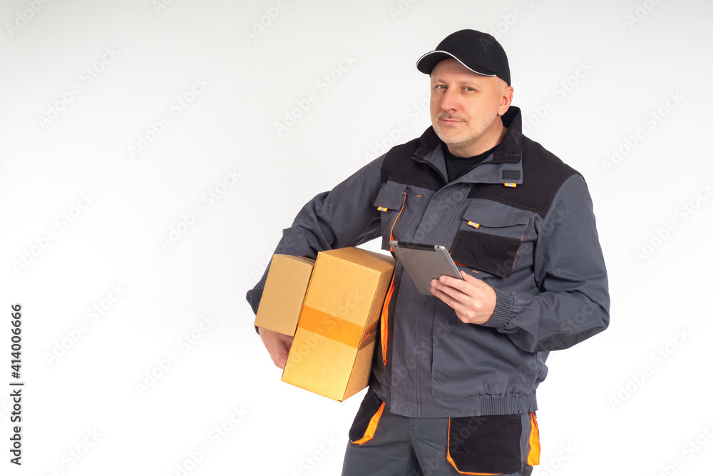 Home delivery of goods. The smiling courier looks at the camera. A man with boxes and a tablet PC delivers an order to a customer. Delivery service.