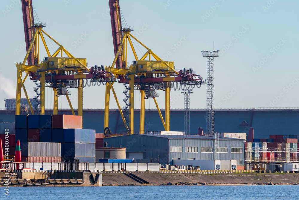 Commercial port. View of the warehouse in the port and gantry cranes. Cranes and containers with cargo in the port. Transportation of goods by water transport. Loading and unloading operations.