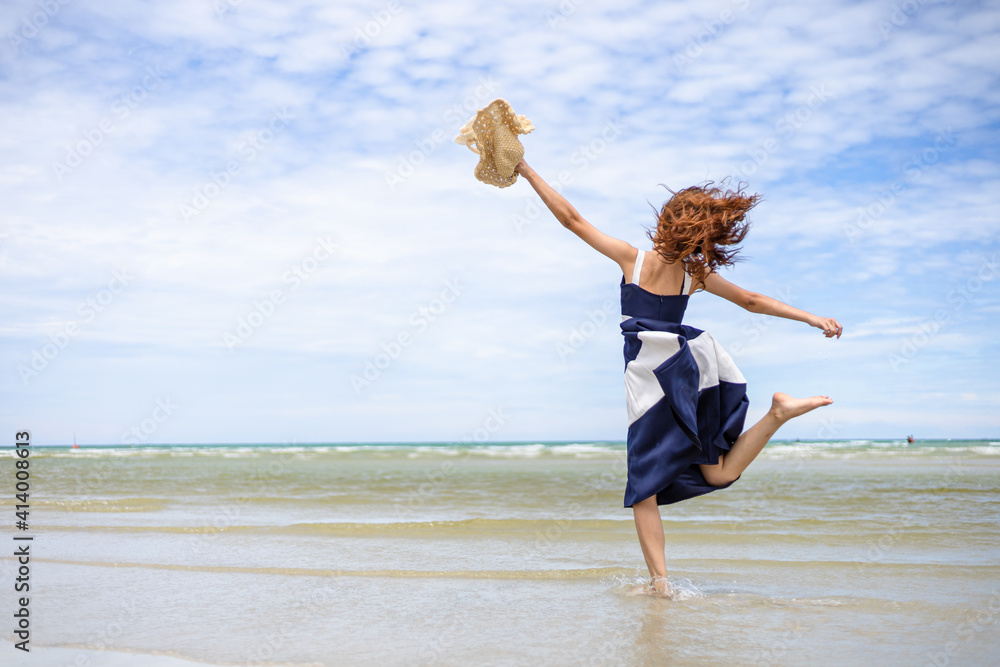 Obraz premium Woman barefoot jump in the water on summer along wave of sea water and sand on the beach.