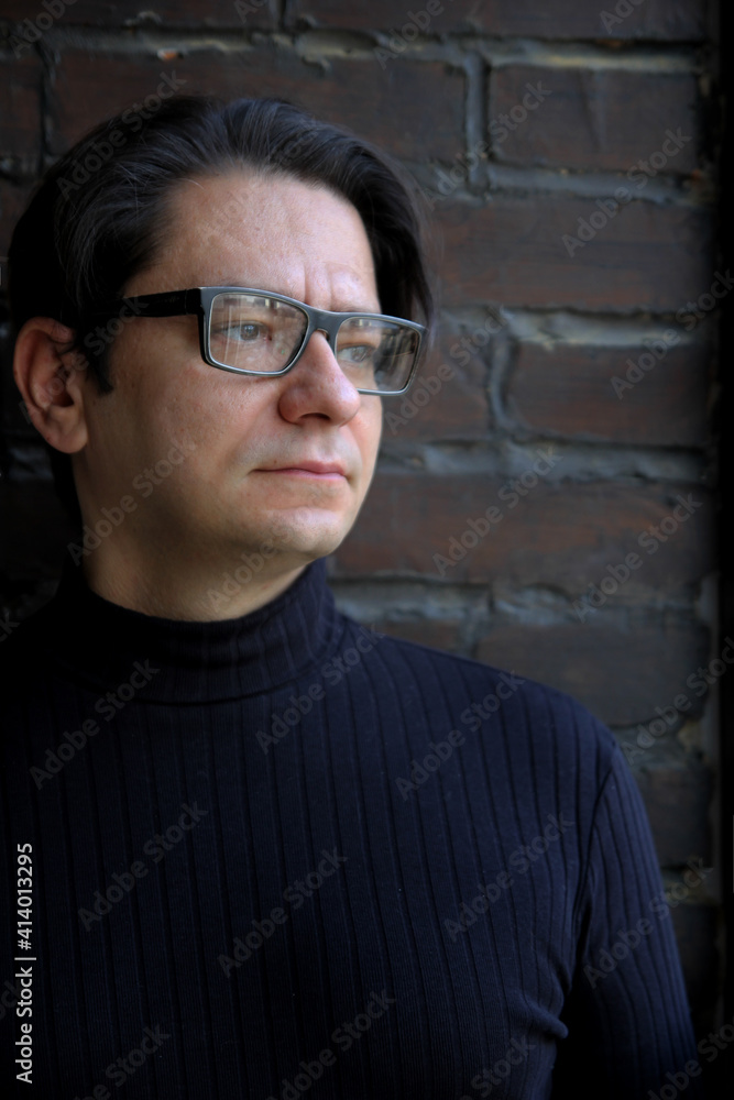 Obraz premium A man with glasses on a brick wall background. Scientist. Psychological picture.