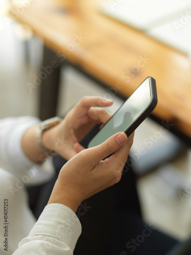 Female hand working with smartphone while sitting in workplace