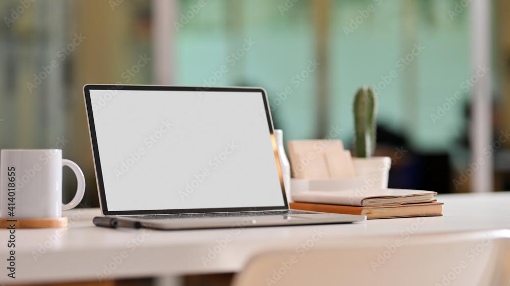 Worktable with laptop, a glass of water, stationery and decorations in living room Worktable with laptop, a glass of water, stationery and decorations in living room