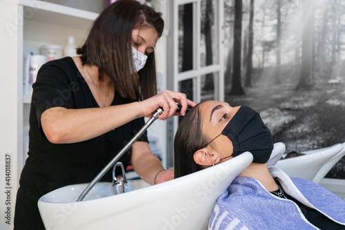 Young hairdresser washing her client's hair