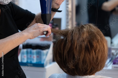 Young hairdresser combing her client's hair