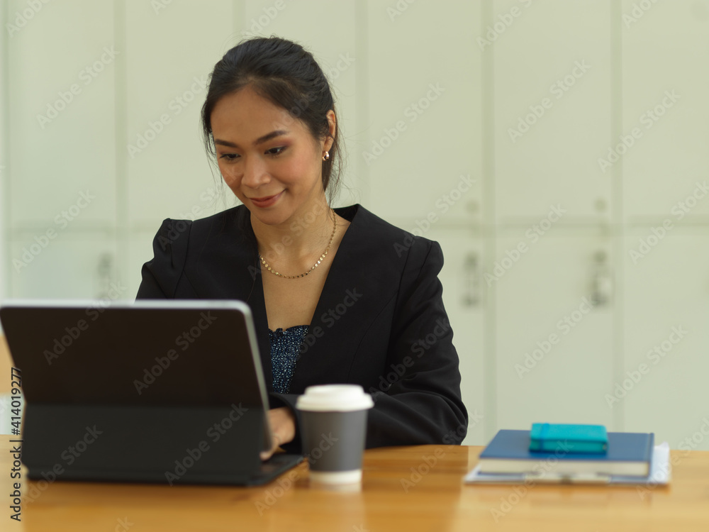 Businesswoman smiling and working with digital tablet on the table in co-working space