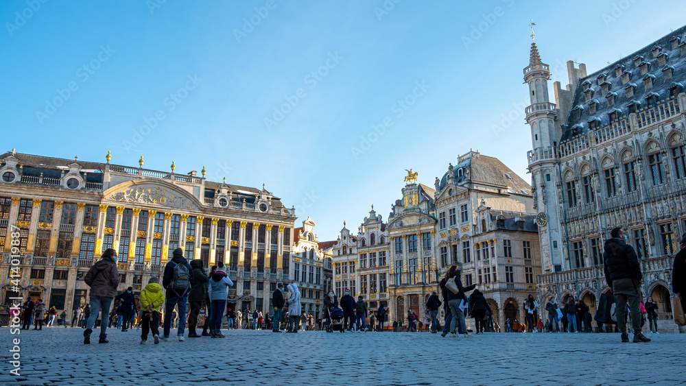 View of the Grand Place in Brussels in  winter season on a beautiful sunny day. Tourists are walking around and discovering the beautiful architecture and facade - Belgium city tour