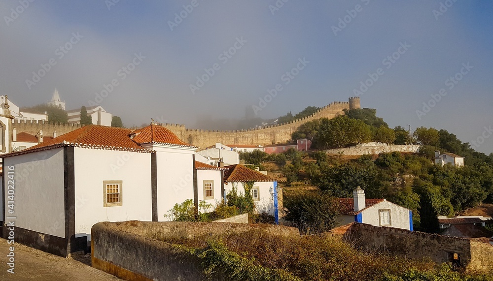 Obidos, Portugal : Cityscape of the town with medieval houses, wall and the Albarra tower. Obidos is a medieval town still inside castle walls, and very popular among tourists