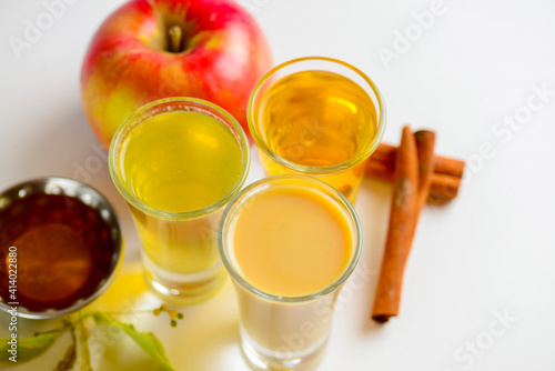 Fresh organic apple cider with apples and cinnamon over white background. Close up three glasses.