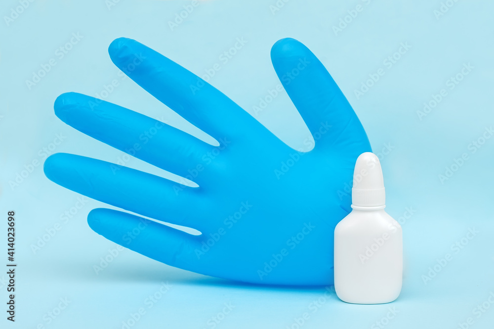 Medical glove and white spray bottle on a blue background. Medical glove and white spray bottle on a blue background.