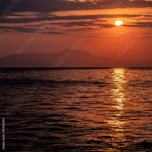 orange fiery sundwn sky with some clouds over calm sea, nature background © Dimitrios