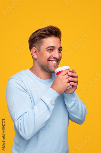 Happy young guy enjoying hot drink