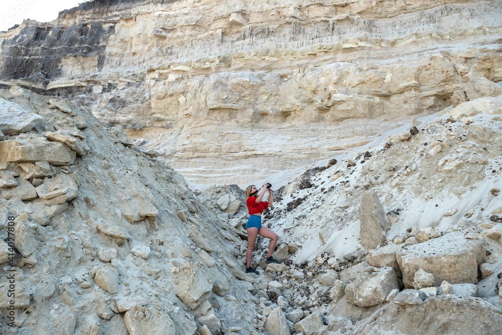 stylish young woman travels through canyons and sand rocks taking photos