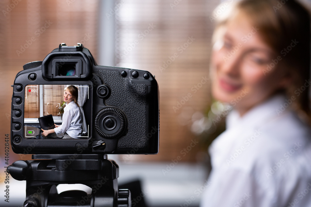 Young female blogger looking at camera and talking a video recording holding laptop at home. Social media blogger or content maker. Blonde smiling speaking in front of camera for vlog. Video tutorial Young female blogger looking at camera and talking a video recording holding laptop at home. Social media blogger or content maker. Blonde smiling speaking in front of camera for vlog. Video tutorial