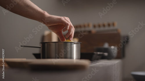 man hand put fettuccine into boiling water in saucepan