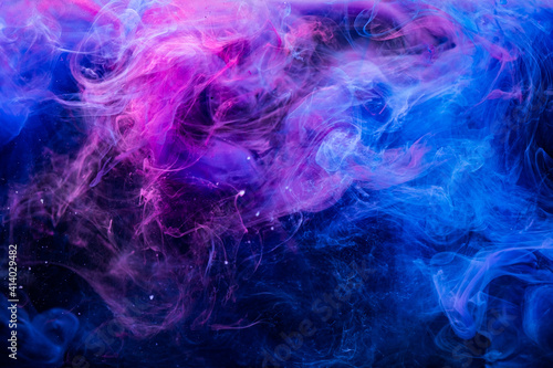 Color fume. Creative background. Paint in water. Ultraviolet mystic air. Glowing vibrant neon blue magenta pink fog spreading on dark.