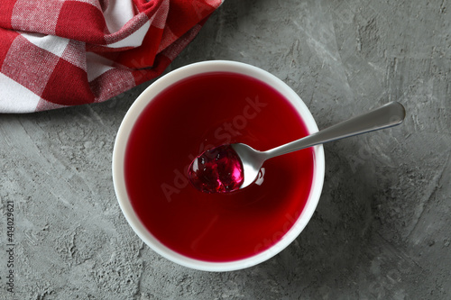 Concept of dessert with bowl of red jelly on gray textured table