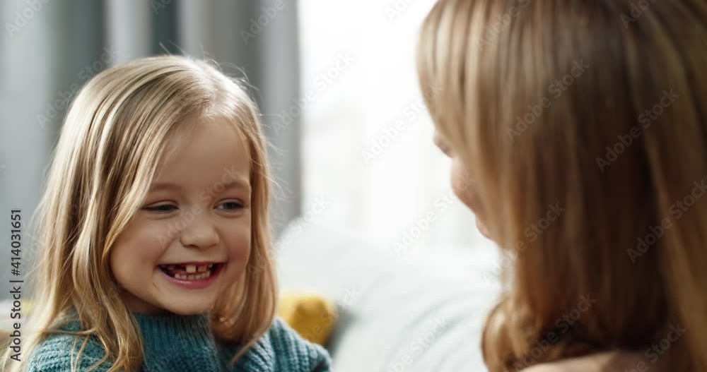 Close up of little happy girl laughing hugging mom. Mom tickles her daughter sitting at home on couch. Close up of little happy girl laughing hugging mom. Mom tickles her daughter sitting at home on couch.
