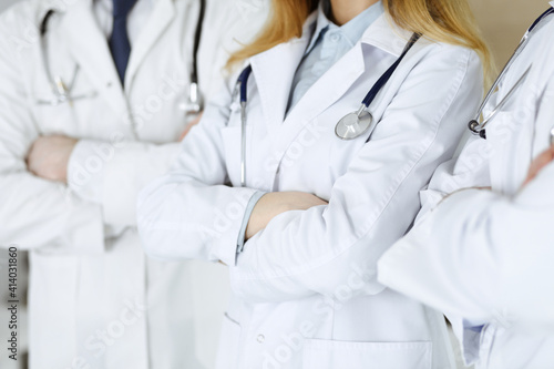 Group of unknown doctors standing as a team with arms crossed in hospital office, close-up. Medical help, insurance in health care and medicine concept