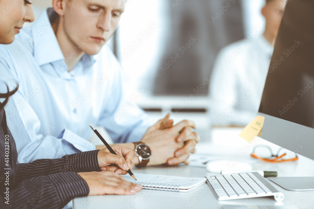 Business woman and man are discussing questions while using computer and blocknote in modern office, close-up. Teamwork in business Business woman and man are discussing questions while using computer and blocknote in modern office, close-up. Teamwork in business