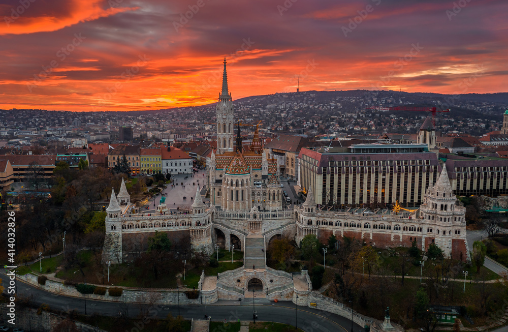 Budapest, Hungary - Aerial view of a dramatic golden sunset behind the famous Fisherman's Bastion (Halaszbastya) and Matthias Church on a winter afternoon. Festive lights and christmas decoration