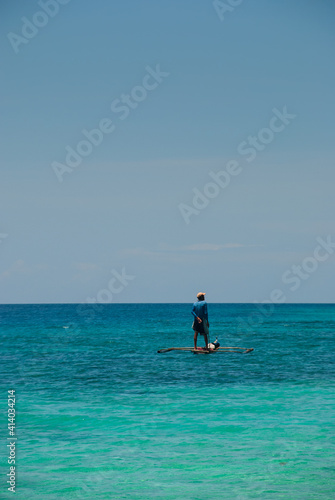 Fisherman standing on his small boat in a calm sea © nifty50gallery