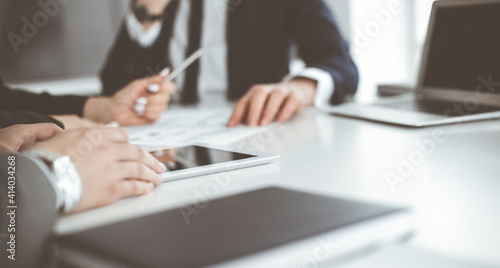 Unknown businessmen and woman sitting, working and discussing questions at meeting in modern office, close-up