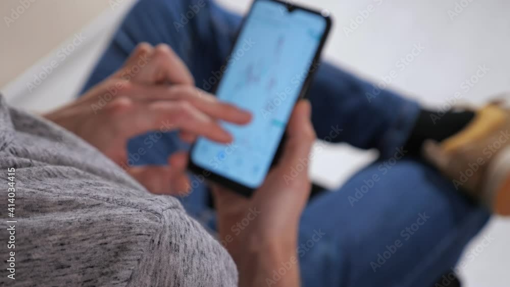 Unrecognizable man with phone examines stock market charts analysis. Unrecognizable man with phone examines stock market charts analysis.