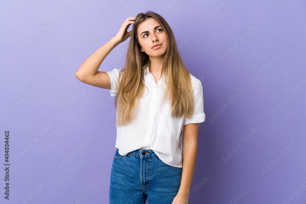 Young woman over isolated purple background having doubts while scratching head Young woman over isolated purple background having doubts while scratching head